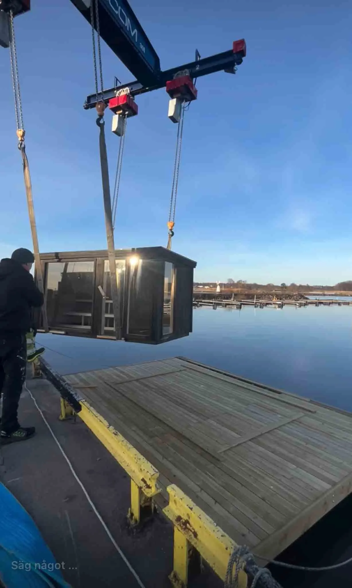 Cranes lifting Bastuflotten Mariestad floating sauna into place on Lake Vänern