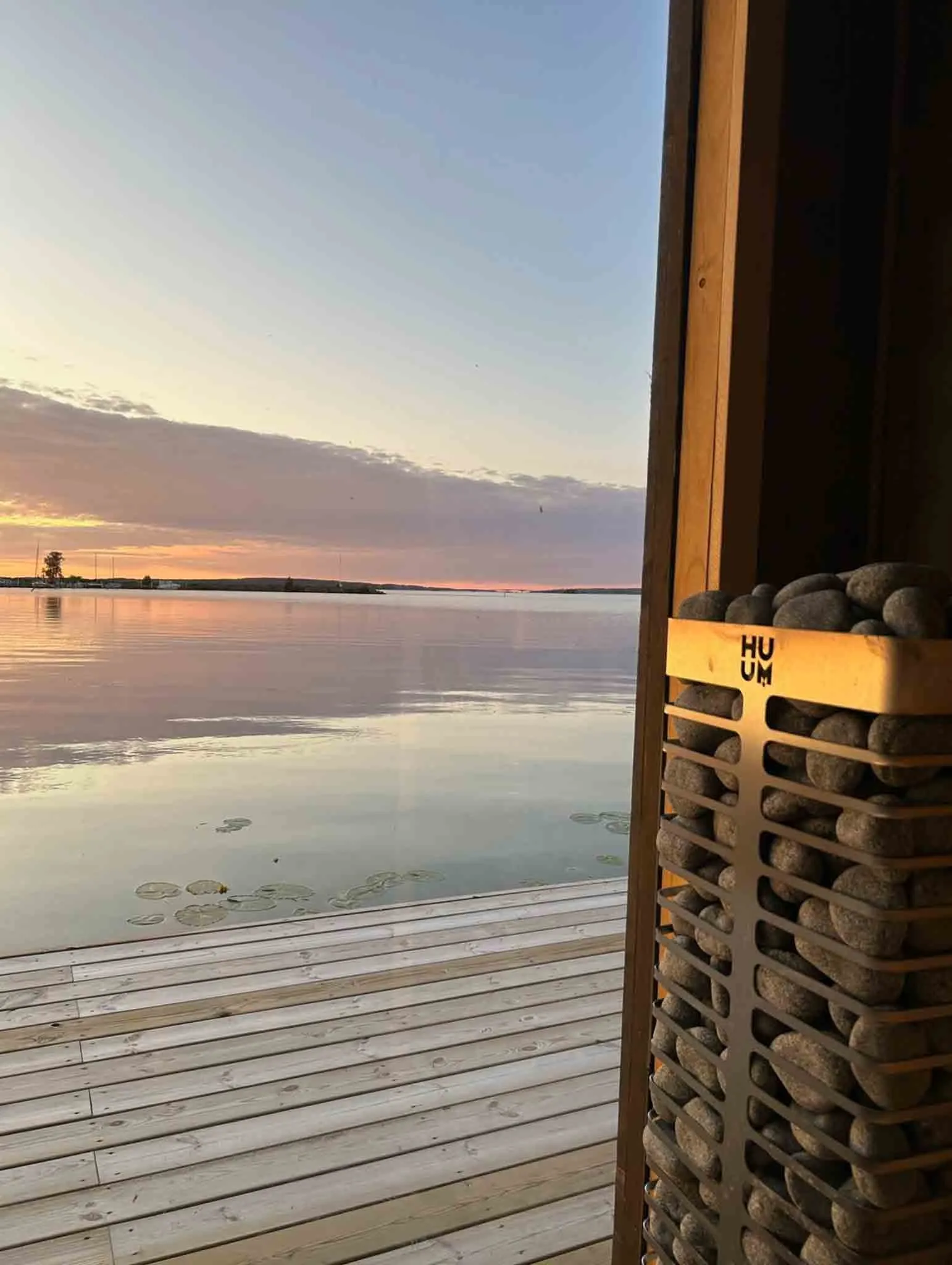 The view from the sauna — open water, quiet reeds, and the sunset over Lake Vänern.