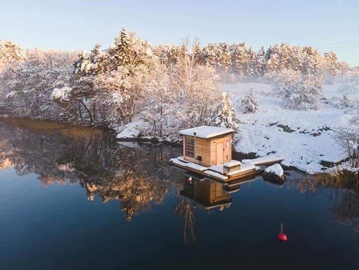Small floating sauna on a lake in a snowy winter landscape