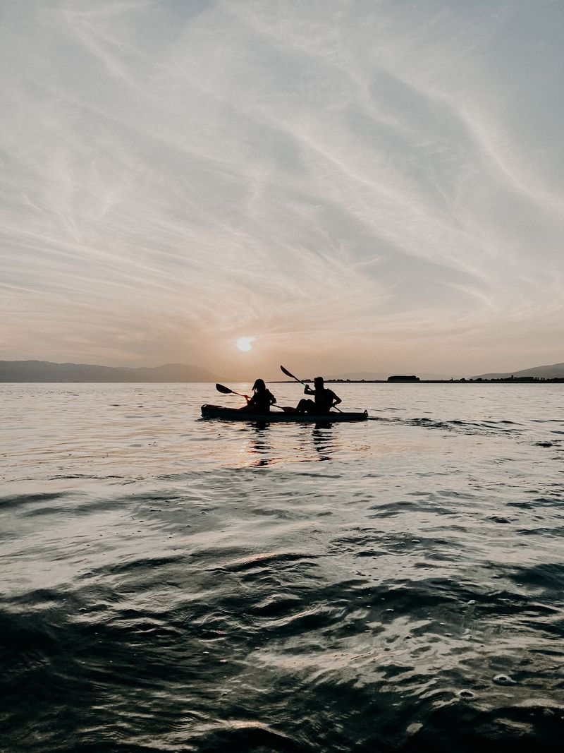 Two people kayaking on calm water at sunset