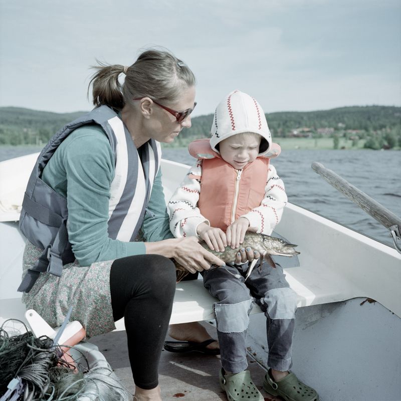Mother and young son holding a freshly caught pike in a boat