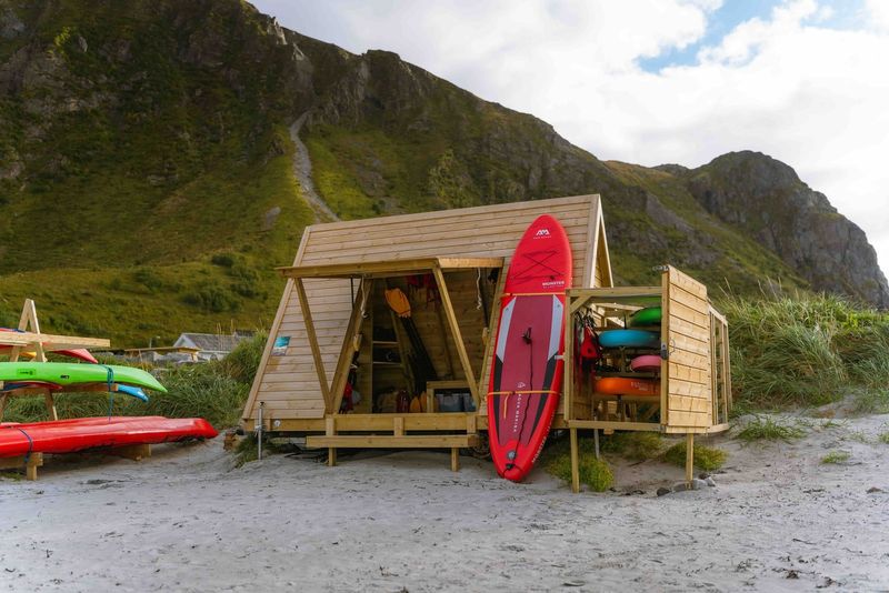 Lofoten Wild's self-service rental box with SUPs, paddles and life jackets on a beach in Lofoten, Norway