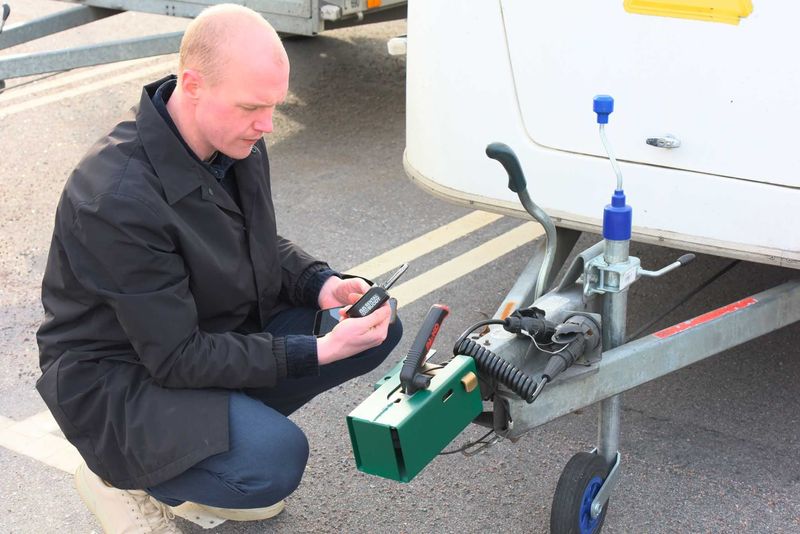 Renter unlocking the hitch lock of a rental trailer with the code on his phone