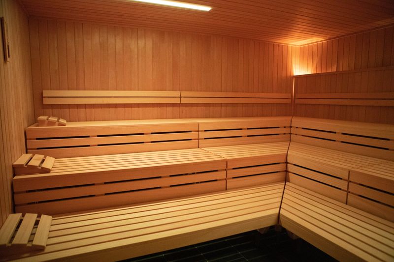 Warmly lit wooden sauna with several rows of benches