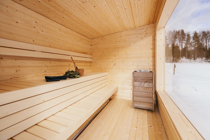 Bright wooden sauna with a large window overlooking a snowy landscape
