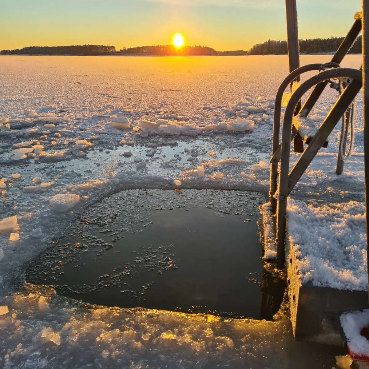 Sunlit ice hole in the frozen bay at Strandstuviken for a winter dip after the sauna